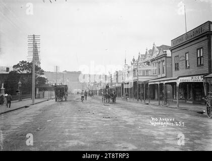 Blick auf die Victoria Avenue, Wanganui, Neuseeland, Blick auf die Victoria Avenue, Wanganui, Neuseeland, Blick auf das Postamt, mit dem Licht auf der Spitze des Watt Fountain an der Kreuzung mit der Victoria Avenue in der Mitte. Der Turm der Post ist in der Mitte rechts zu sehen, die Straße ist von Geschäften gesäumt, und es gibt mehrere Pferdewagen auf der Straße. Vor Dezember 1908, als der Brunnen an einen anderen Ort verlegt wurde, um Platz für die neue Straßenbahn zu schaffen, die im Dezember 1908 offiziell eröffnet wurde Stockfoto