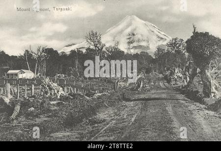 Postkarte. Mount Egmont, Taranaki. T Avery, Buchhändler, New Plymouth, N.Z. CA 1905, zeigt einen Blick auf den Mount Taranaki von einer unbefestigten Straße zwischen freigelegten Feldern, mit einem Bauernhaus auf der linken Seite Stockfoto