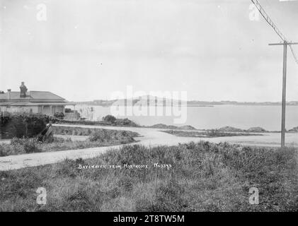 Bayswater von Northcote, Auckland, Neuseeland, Blick auf Bayswater von der Princes Street, Northcote mit Blick auf die Shoal Bay mit Bayswater Wharf und Rangitoto Island in der Ferne. Links im Vordergrund befindet sich ein einstöckiges Haus Stockfoto