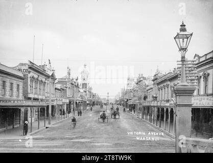 Blick auf Victoria Avenue, Wanganui, Neuseeland, Blick auf Victoria Avenue, Wanganui, Neuseeland von der City Bridge. Der Uhrturm der Post ist in der Mitte links zu sehen, die Straße ist von Geschäften gesäumt, und es kommen mehrere Pferdewagen, die auf die Kamera zufahren. In der Mitte des Bildes ist der Watt-Brunnen zu sehen. Vor Dezember 1908. Der Brunnen wurde verlegt, um Platz für eine neue Straßenbahnlinie zu schaffen, die im Dezember 1908 eröffnet wurde Stockfoto