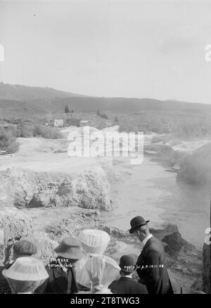 Tikitere, Rotorua County, Blick auf das Thermalgebiet von Tikitere, bei dem eine Gruppe von Besuchern durch die Gegend geführt wird. Es gibt zwei Häuser in der Mitte. Im Jahr 1908 Stockfoto