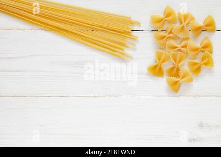 Spaghetti, Farfalle, rohe Pasta, auf weißem Holzbrett Hintergrund, Draufsicht, Platz zum Kopieren von Text. Stockfoto