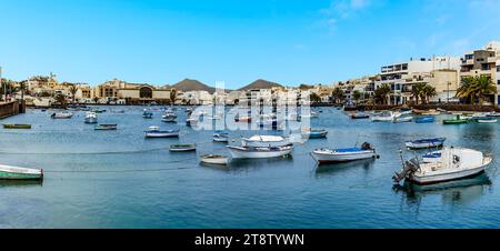 Ein Panoramablick auf die idyllische Szene der kleinen Boote, die an einem hellen sonnigen Nachmittag in der Lagune von Charco de San Gines in Arrecife, Lanzarote, ankern Stockfoto