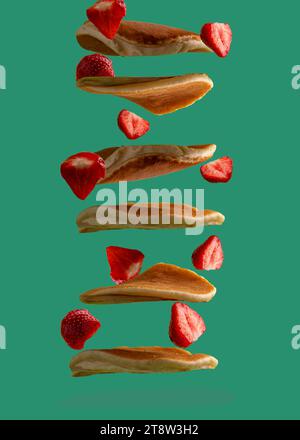 Fallende Pfannkuchen und Erdbeeren auf grünem Hintergrund Stockfoto