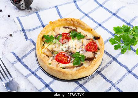 Köstliche Quiche mit Hühnerfleisch, Pilzen, Tomaten und Kräutern Stockfoto