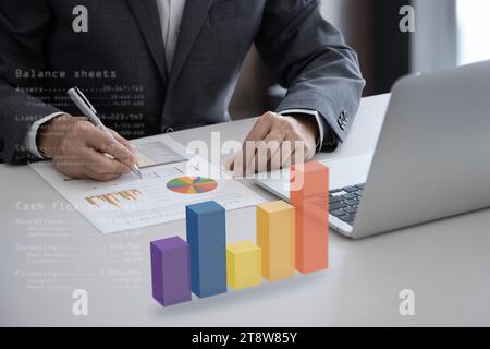 Geschäftsmann mit dreidimensionalem Balkendiagramm auf dem Schreibtisch, das Finanzberichte auf Geschäftsvorteile und Kapitalrendite überprüft Stockfoto