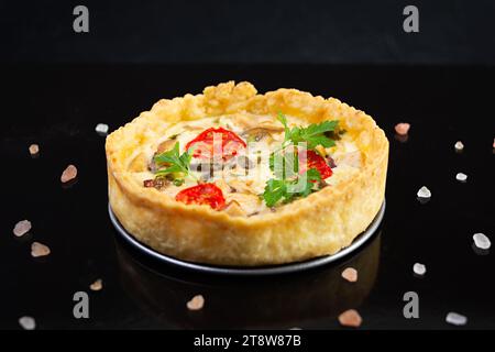 Köstliche Quiche mit Hühnerfleisch, Pilzen, Tomaten und Kräutern Stockfoto