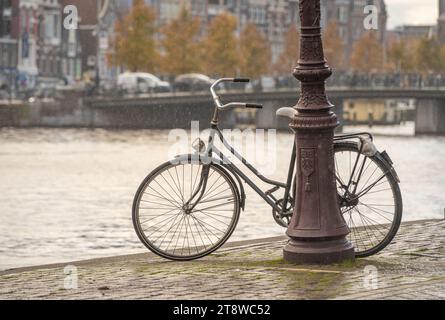 Altes holländisches Fahrrad am Kanal in Amsterdam an einem regnerischen Herbsttag Stockfoto