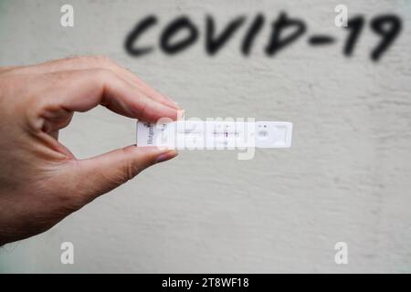 Worms, Rheinland-Pfalz - 21. November 2023: Ein alter Mann hält einen positiven Corona-Schnelltest in der Hand. Wandbeschriftung COVID-19 FOTOMONTAGE *** Alter Mann hält einen positiven Corona Schnelltest in der Hand. Wand mit Schriftzug COVID-19 FOTOMONTAGE Credit: Imago/Alamy Live News Stockfoto