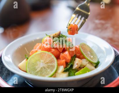 Scharfer Lachs in Scheiben mit Obstsalat in einer weißen Keramikschale. Fusion Food Vorspeise Stockfoto