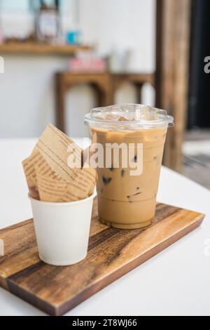 Iced Latte Kaffee in Plastikglas und Dessert Chocolate Ball auf Holztablett im Coffee Shop Stockfoto