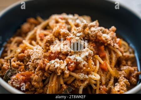 Traditionelle Spaghetti-Tomatensoße Hackfleisch vom Schwein und Käse italienischer Gerichte auf schwarzem Teller auf Holztisch Stockfoto