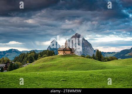 Hölzerne Stoos-Kirche auf grünem Hügel vor dem Großen Mythen im Sommer im Kanton Schwyz, Schweiz Stockfoto