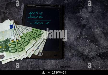 100 Euro-Banknoten, die auf dem Tisch verteilt sind und Steuern zahlen Inflation in Europa Stockfoto