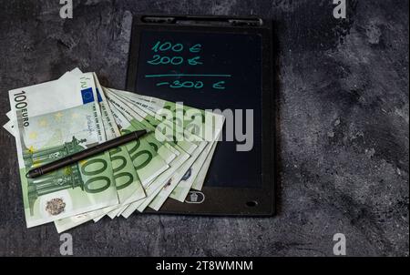 100 Euro-Banknoten, die auf dem Tisch verteilt sind und Steuern zahlen Inflation in Europa Stockfoto