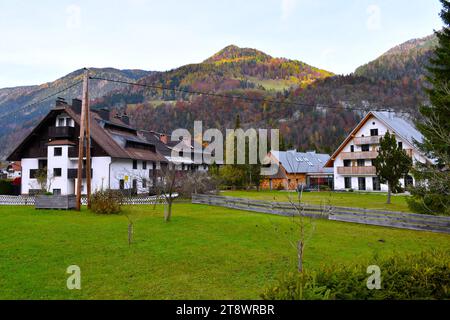 Häuser in Gozd Martuljek Dorf in Gorenjska, Slowenien mit herbstfarbenem Wald bedeckt Karavanke Berge Stockfoto