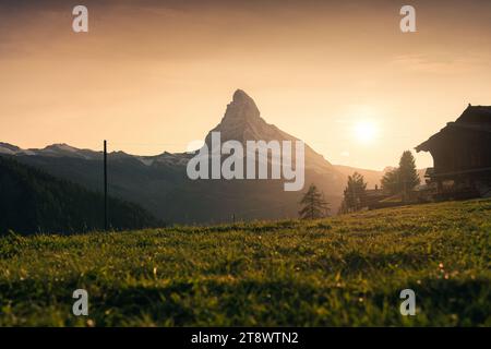 Gemütliche Landschaft des Sonnenuntergangs über dem Matterhorn mit Holzhütte auf Weide in ländlicher Szene in Zermatt, Schweiz Stockfoto