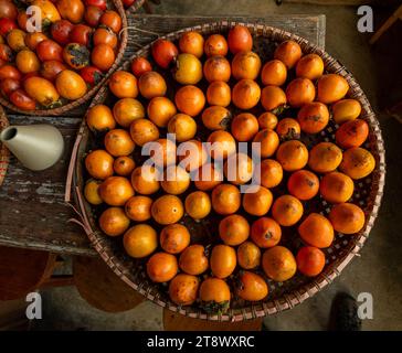 Reife orangefarbene Persimmonen. Auf dem Tisch auf dem Markt. Ein Haufen Bio-Persimmon-Früchte auf einem lokalen Bauernmarkt in Dalat, Vietnam. Persimmon BA Stockfoto