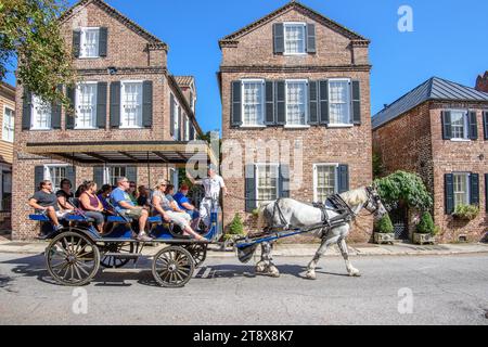 Pferdekutsche mit Touristen, die die Fassaden der Societe Francaise und die historische traditionelle Wohnarchitektur in Charleston, SC, genießen. Stockfoto