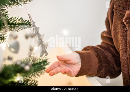 Kleines Mädchen, das den Weihnachtsbaum mit silberner Dekoration dekoriert Stockfoto