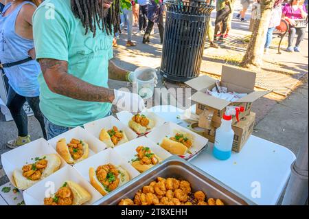 NEW ORLEANS, LA, USA – 19. NOVEMBER 2023: Unbekannter Arbeiter streut Koriander auf Shrimps-Poboy-Sandwiches beim Oak Street Poboy Festival Stockfoto
