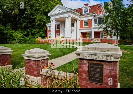 Ahornholz Hausschild am Eingang des Minnetrista Museum and Gardens mit Blumen und blauem Himmel Stockfoto