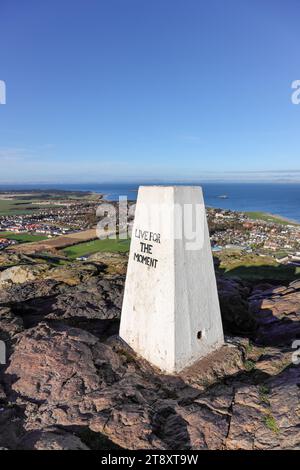 Der Gipfel Trig Point on North Berwick Law mit der Botschaft „Live for the Moment“, North Berwick, East Lothian, Schottland, Vereinigtes Königreich. Stockfoto