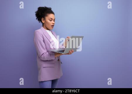 Die junge, kluge hispanische Brünette-Führerin mit lockigen Haaren in der Jacke benutzt Laptop für geschäftliche Angelegenheiten Stockfoto