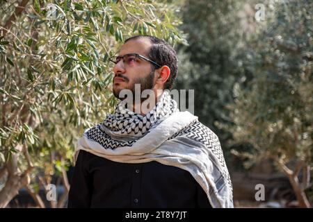 Porträt für Männer, die Keffiyeh auf dem Olivenbaumfeld tragen, mit schwarzem Hintergrund und schwarzen Hemden auch mit wütendem Gesichtsausdruck Stockfoto