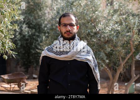 Porträt für Männer, die Keffiyeh auf dem Olivenbaumfeld tragen, mit schwarzem Hintergrund und schwarzen Hemden auch mit wütendem Gesichtsausdruck Stockfoto