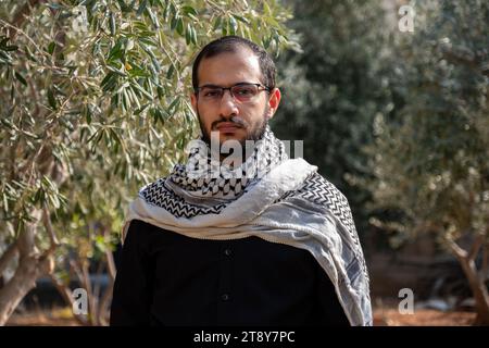 Porträt für Männer, die Keffiyeh auf dem Olivenbaumfeld tragen, mit schwarzem Hintergrund und schwarzen Hemden auch mit wütendem Gesichtsausdruck Stockfoto