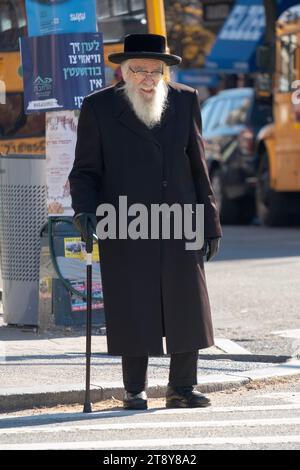 Ein älterer chassidischer Mann mit einem Stock, wahrscheinlich aus der Satmar-Dynastie, überquert die Straße an einem kühlen späten Herbsttag im Jahr 2023. In Brooklyn, New York. Stockfoto