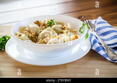 Ukrainischer Vareniky oder Pierogi gefüllt mit Kartoffeln und Pilzen, serviert mit gebratenen Zwiebeln. Holztischhintergrund. Hochwertige Fotos Stockfoto