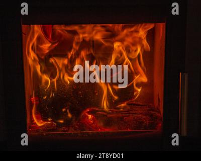 Intensive Flammen verbrennen Holz in einem geschlossenen Kamin mit sichtbarer Glut und Wärmeausdruck Stockfoto