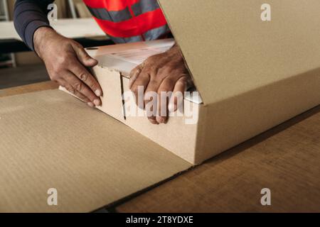 Ein Mann verpackt Möbelprodukte in Pappverpackungen. Möbelherstellung Stockfoto