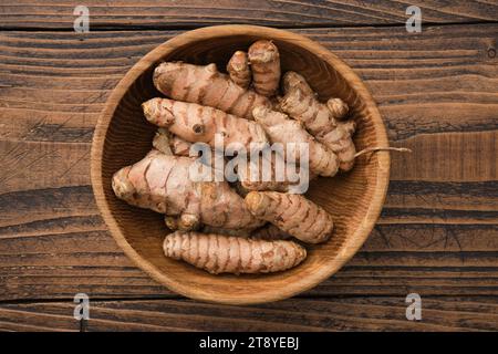 Hölzerne Schüssel mit Curcuma-Wurzeln. Kurkuma-Gewürz. Draufsicht, flach. Stockfoto