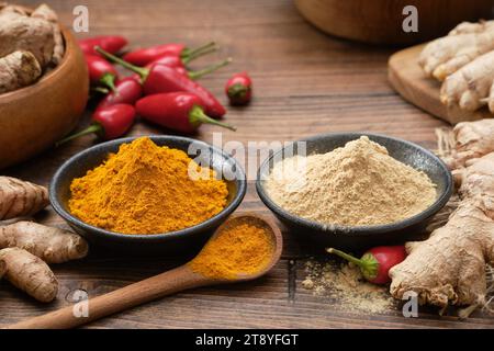 Schüsseln mit Ingwer und Curcuma zu Pulver gemahlen. Rote Chilischoten, ganze Ingwer- und Kurkuma-Wurzeln auf dem Küchentisch. Zutaten zum Kochen und Ay Stockfoto