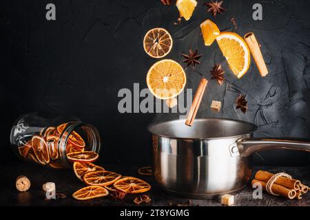 Glühwein, das Hauptgetränk auf Weihnachtsmärkten. Herabfallende Zutaten auf dunklem Hintergrund. Weihnachtsbanner. Stockfoto