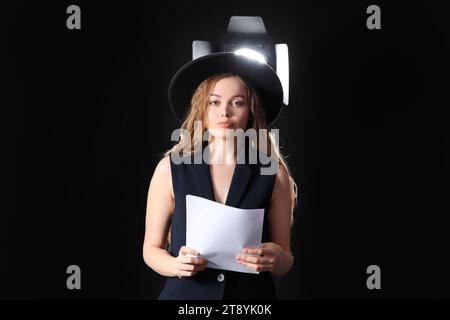 Schöne Schauspielerin mit Drehbuch auf dunklem Hintergrund Stockfoto