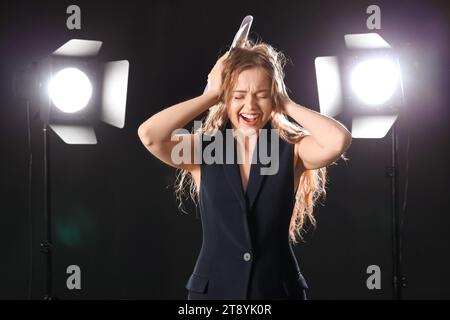 Schöne Schauspielerin mit Drehbuch auf dunklem Hintergrund Stockfoto