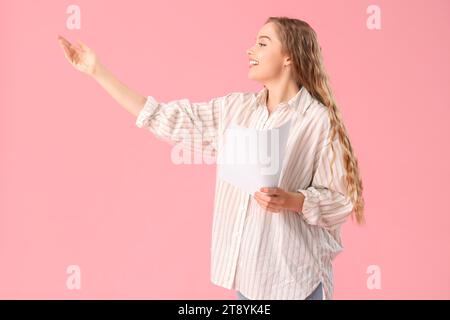 Wunderschöne Schauspielerin mit Drehbuch auf rosa Hintergrund Stockfoto