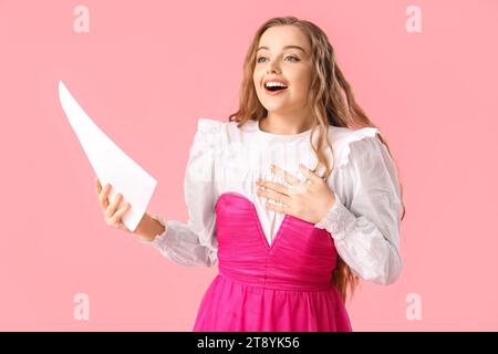 Wunderschöne Schauspielerin mit Drehbuch auf rosa Hintergrund Stockfoto