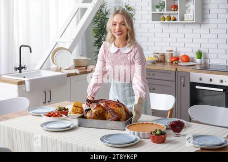 Schöne junge Frau mit leckerem gebackenem truthahn am Tisch in der Küche. Thanksgiving-Feiertag Stockfoto
