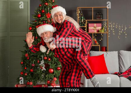 Glückliches, reifes Paar, das sich am Weihnachtsabend zu Hause amüsiert Stockfoto