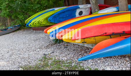 Mehrere farbenfrohe Kajaks können an einem Strand an einem See gemietet werden. Stockfoto