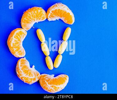 Mandarinenscheiben, die den Buchstaben „C“ bilden, und Vitamin-C-Tabletten, die den Buchstaben „V“ bilden. Das Konzept der künstlichen und natürlichen Vitamin-C-Quellen Stockfoto