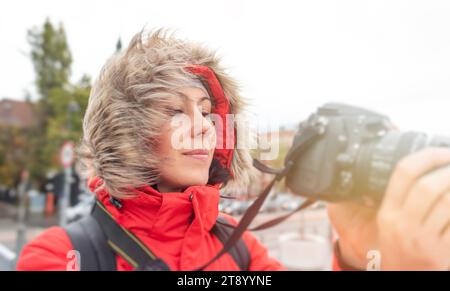 Fotografin in Winterjacke mit Kamera auf der Straße. Stockfoto