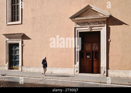 Rom, Italien - 29. Oktober 2023: Ein alter Mann, der vor einer typischen römischen Architektur-Fassade in der Innenstadt (Nostra Signora del Sacro Cu Stockfoto