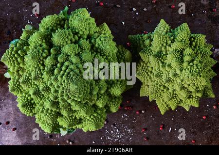 Zwei Romanesco-Kohl auf einem Backblech mit Kräutern, Blick von oben und dunkles Ambiente Stockfoto