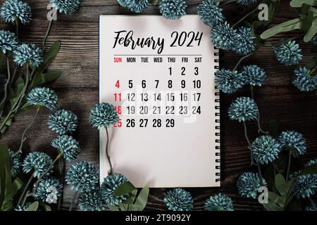 Monatskalender Februar 2024 mit Blumenstrauß Dekoration auf hölzernem Hintergrund Stockfoto
